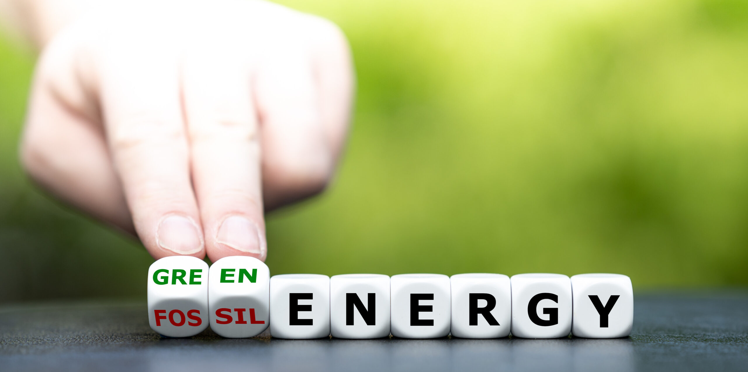 Hand turns dice and changes the expression “fossil energy” to “g
